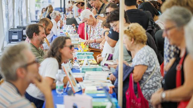 Des visiteurs consultent des livres lors de la 15eme edition de la manifestation "Le Livre sur les Quais", LSQ, ce samedi 31 aout 2024 a Morges. [KEYSTONE - Valentin Flauraud]