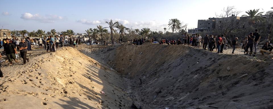 Palestinians inspect a crater as they search for missing people following Israeli airstrikes on a designated humanitarian zone of Al-Mawasi, west of Khan Younis, southern Gaza Strip, 10 September 2024. According to Gaza's civil emergency service, at least forty people were killed and more than 60 injured, with many still trapped under the rubble, following the Israeli army's airstrikes early on 10 September. The Israeli army said it targeted a Hamas command center in the Al-Mawasi area. [Keystone - EPA/HAITHAM IMAD]