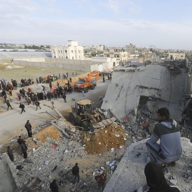 Des palestiniens observant la destruction d'un immeuble de Rafah par l'armée israélienne. [Keystone/AP Photo - Hatem Ali]