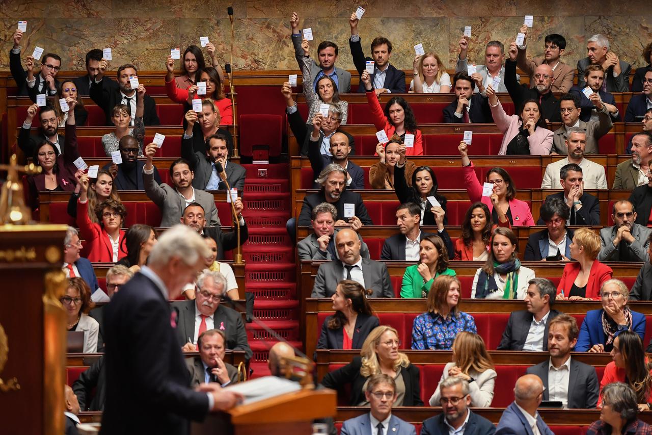 Les députés LFI ont symboliquement brandi des cartes d'électeurs dans l'hémicycle, en réaction à la déclaration de politique générale du Premier ministre Michel Barnier, dont ils considèrent l'arrivée à Matignon comme un contournement du résultat des dernières élections. [KEYSTONE - JULIEN MATTIA]