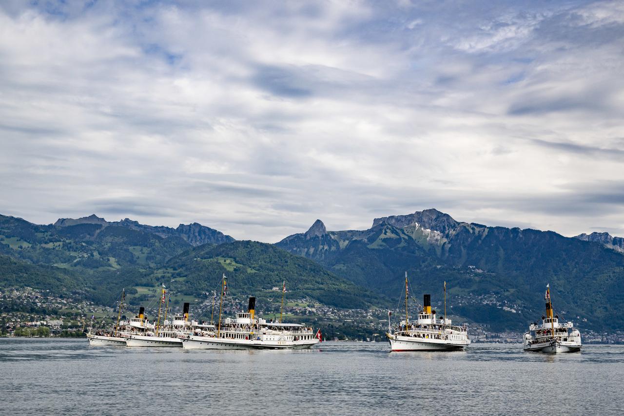 L'"Italie", le "Savoie", le "Vevey", "La Suisse" et le "Montreux" au large de Vevey lors de la Parade navale de la CGN le 26 mai 2024, devant la Dent de Jaman et les Rochers de Naye. [KEYSTONE - JEAN-CHRISTOPHE BOTT]