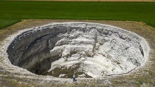 Cette photographie aérienne montre l'agriculteur Yigit Aksel marchant autour d'un gouffre géant formé au milieu des champs à Karapinar, dans la province de Konya en Anatolie centrale, le 23 juin 2024. [AFP - YASIN AKGUL]