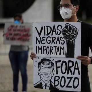 Un activiste tient un panneau indiquant "Black Lives Matter" en portuguais. [Keystone/AP Photo - Silvia Izquierdo]