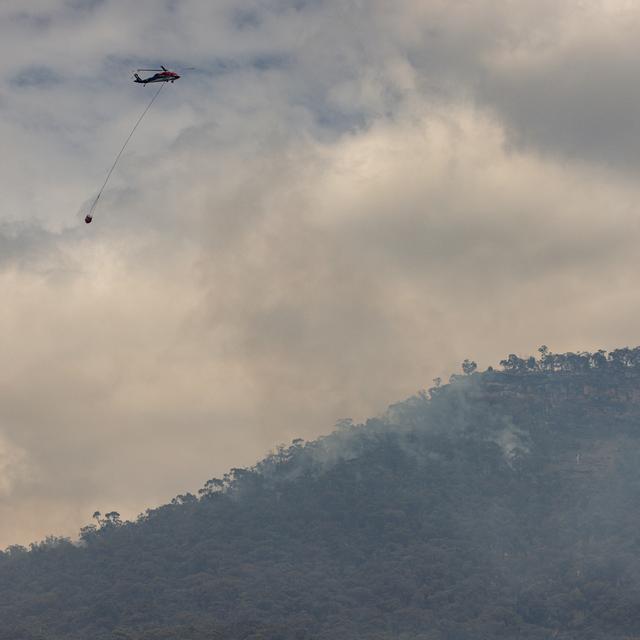 Les pompiers australiens tentent vendredi de maîtriser un immense feu de brousse se propageant à travers un parc national du sud-est du pays. [Keystone - Diego Fedele]