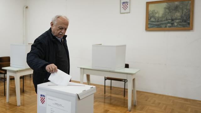 Un homme glisse un bulletin dans une urne pour la présidentielle en Croatie. [AP Photo/Keystone - Darko Bandic]