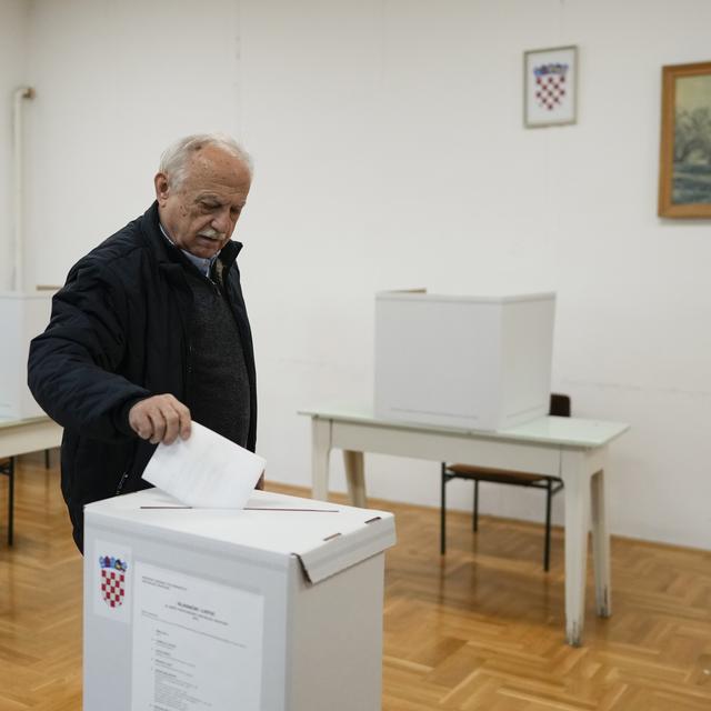 Un homme glisse un bulletin dans une urne pour la présidentielle en Croatie. [AP Photo/Keystone - Darko Bandic]