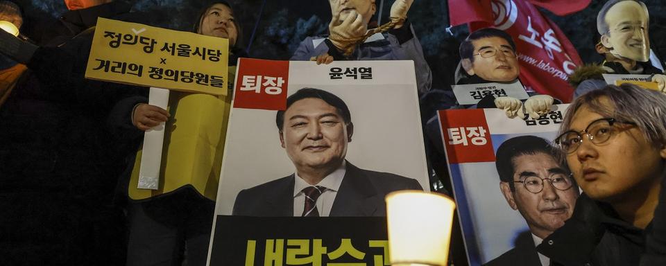 Des manifestants tenant des affiches demandant l'arrestation du président sud-coréen Yoon Suk Yeol et de sa femme Kim Keon Hee. 6 décembre 2024. [EPA/Keystone - JEON HEON-KYUN]