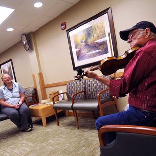 Un homme joue du violon dans un hôpital américain. [Keystone/AP Photo/Missoulian - Michael Gallacher]