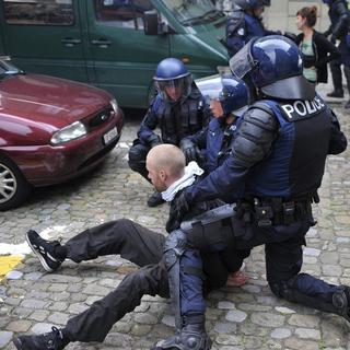 Des policiers qui arrêtent un homme pendant une manifestation contre la violence policière à Fribourg. [Keystone/La Liberté - Alain Wicht]