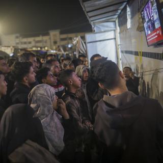 Des Palestiniens regardent les informations à la télévision, le 15 janvier 2025. [Keystone - AP Photo/Jeha Alshrafi]