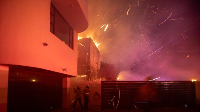 Des pompiers luttent contre l'incendie propagé par une tempête de vent tout près du quartier d'Hollywood à Los Angeles, mercredi soir 8 janvier 2025. [Reuters - Ringo Chiu]