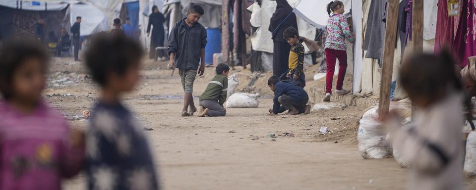 Des enfants palestiniens jouant dans un camp de déplacés à Deir al-Balah, au centre de la Bande de Gaza. 16 janvier 2025. [AP Photo/Keystone - Abdel Kareem Hana]