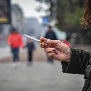 Une fumeuse dans les rues de Milan, où les autorités communales ont durci les règles concernant le fait de fumer en public. [EPA / Keystone - MATTEO CORNER]