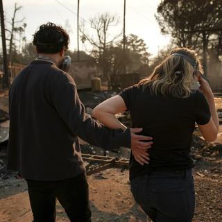 Un couple retourne dans les débris de leur maison du quatrier d'Altadena, détruit par les incendies qui dévastent la région de Los Angeles. [AP Photo - Jae C. Hong]