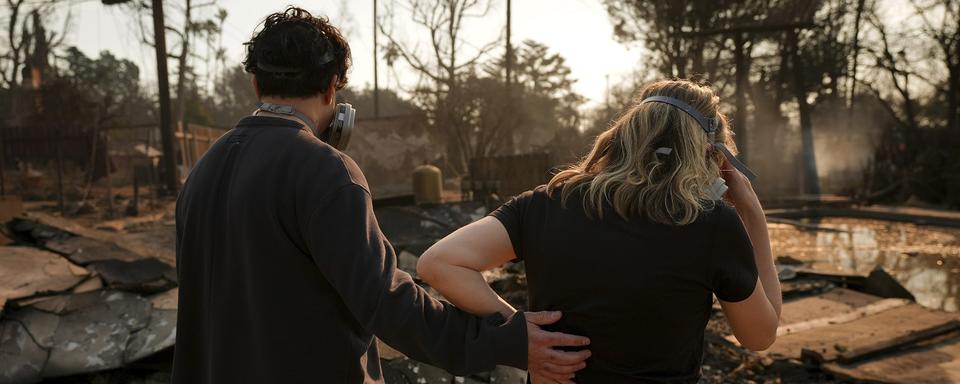 Un couple retourne dans les débris de leur maison du quatrier d'Altadena, détruit par les incendies qui dévastent la région de Los Angeles. [AP Photo - Jae C. Hong]