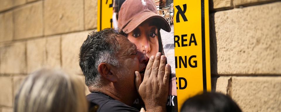 Le père de Liri Albag, otage du Hamas, pleurant devant un portrait de sa fille lors d'une manifestation à Tel Aviv, Israël. Le 14 octobre 2023. [AP Photo/Keystone - Francisco Seco]