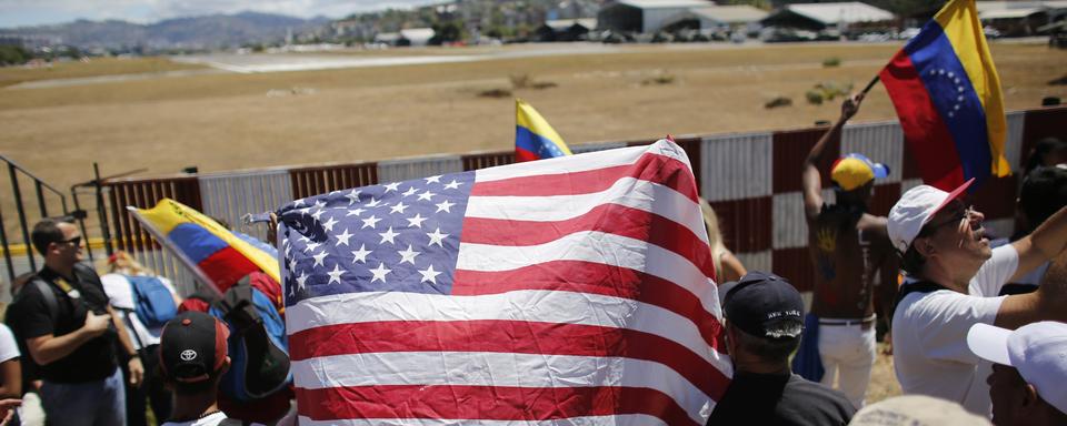 Une personne brandit un drapeau américain au milieu des drapeaux nationaux vénézuéliens lors d'une manifestation de partisans de l'opposition à Caracas, au Venezuela, samedi 23 février 2019. [Keystone - AP Photo/Ariana Cubillos]