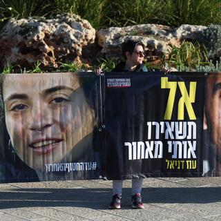 Une manifestante brandit des photos d'otages du Hamas devant la Knesset. Jerusalem, le 14 janvier 2025. [EPA - ABIR SULTAN]