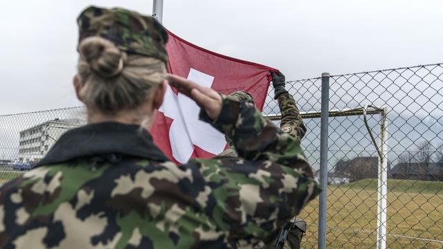 Une soldate salue le drapeau suisse. [KEYSTONE - CHRISTIAN BEUTLER]