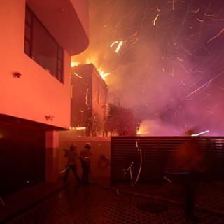 Des pompiers luttent contre l'incendie propagé par une tempête de vent tout près du quartier d'Hollywood à Los Angeles, mercredi soir 8 janvier 2025. [Reuters - Ringo Chiu]