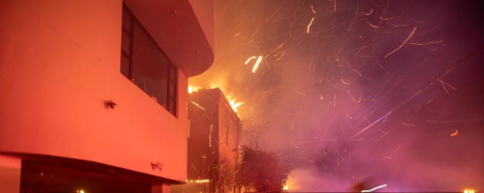 Des pompiers luttent contre l'incendie propagé par une tempête de vent tout près du quartier d'Hollywood à Los Angeles, mercredi soir 8 janvier 2025. [Reuters - Ringo Chiu]