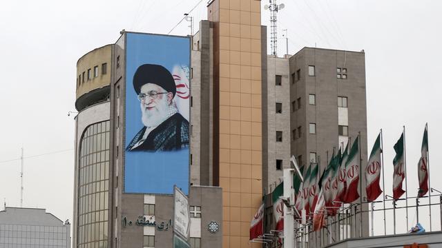 Drapeaux iraniens et peinture murale représentant l'ayatollah Ali Khamenei sur un bâtiment de Téhéran. [KEYSTONE - PETER KLAUNZER]