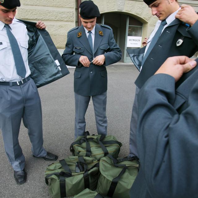 Des militaires ajustent leur tenue de sortie. [Keystone - Martin Ruetschi]