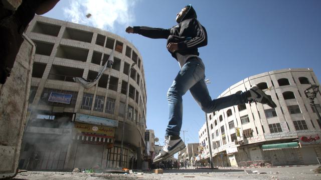 Un Palestinien jettant une pierre contre la sécurité israélienne dans la ville d'Hébron en avril 2013. [Hazem Bader]