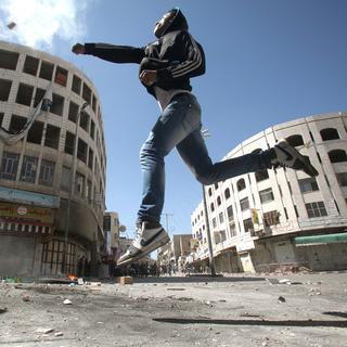 Un Palestinien jettant une pierre contre la sécurité israélienne dans la ville d'Hébron en avril 2013. [Hazem Bader]