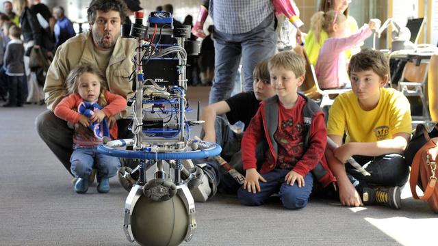 Des visiteurs observent un robot en équilibre et qui se déplace sur un ballon, lors du Festival de Robotique organise par l'EPFL, le 5 mai 2012 à Lausanne. [Martial Trezzini]