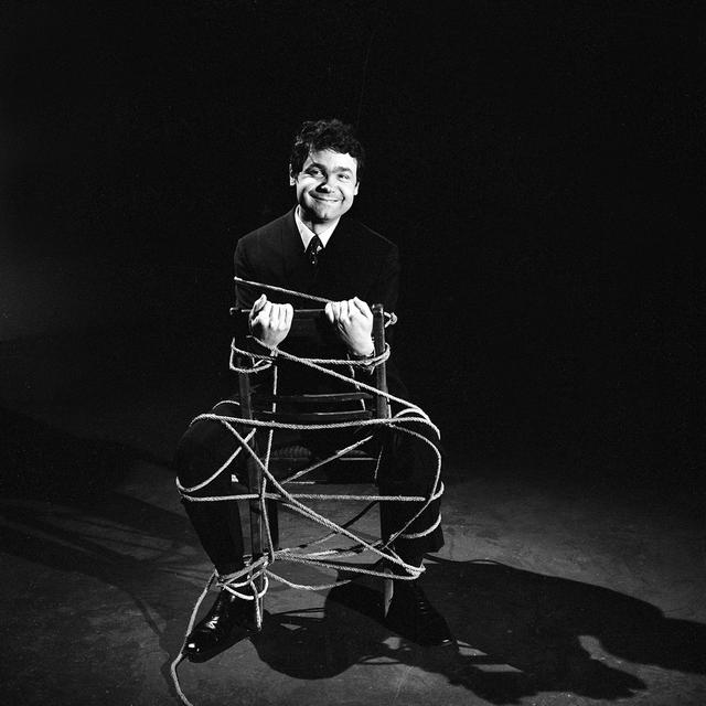 Pierre Perret, ligoté sur une chaise, lors de l'enregistrement de l'émission télévisée "Moi j'aime". [INA / AFP - Louis Joyeux]