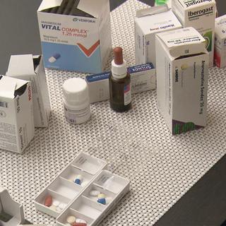 Homme âgé devant un pilulier et de nombreuses boîtes de médicaments. [RTS]