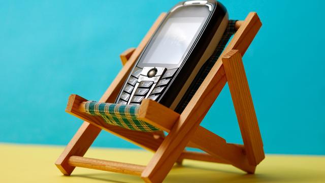 Utiliser son téléphone portable durant les vacances à l'étranger peut coûter cher. Natel, chaise longue, vacances [miqul]