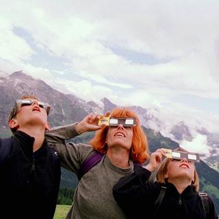 Une famille observe une éclipse solaire partielle à l'aide de lunettes spéciales.
keystone