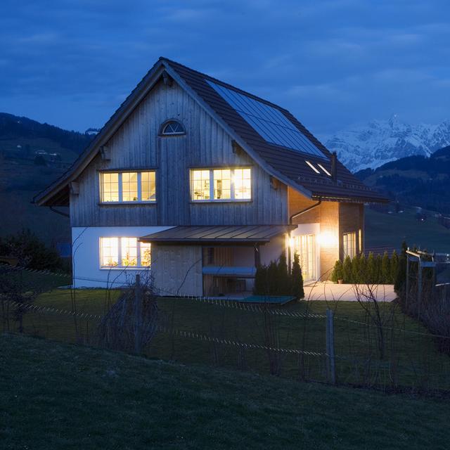 A ecological built one-family house, captured during the dawn in Nesslau, Switzerland, on March 8, 2007. Solar panels which heat up the water in a 10-meter-high cistern in the inside of the house are attached to the rooftop. Minergie connects efficient usage of energy with high quality of life and bearable costs. Used energy is recycled for the usage in the own household with different ways of energy saving.(KEYSTONE/Gaetan Bally) 
Maison nuit, Minergie écologie label, fenêtres, éclairage [Gaetan Bally]