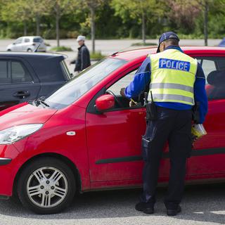 Un agent de la police municipale lausannoise distribue des brochures pour une campagne de prévention routière en 2012. [Jean-Christophe Bott]