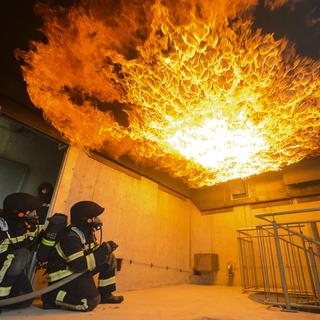 Des pompiers volontaires dans le nouveau simulateur incendie du centre de formation de la Rama dans le canton de Vaud. [Keystone - Laurent Gillieron]