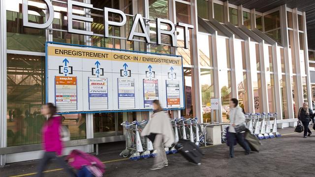 Des passagers marchent devant le terminal 1 de l'aéroport de Genève. [Keystone - Salvatore Di Nolfi]