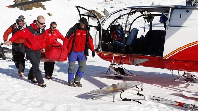 Des sauveteurs d'Air Glaciers portent secours à une skieuse. [Keystone - Jean-Christophe Bott]