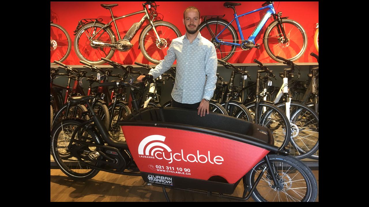 Romain Marandet, patron de la boutique Cyclable, aux côtés d'un modèle de vélo cargo électrique. [RTS - Jérôme Zimmermann]