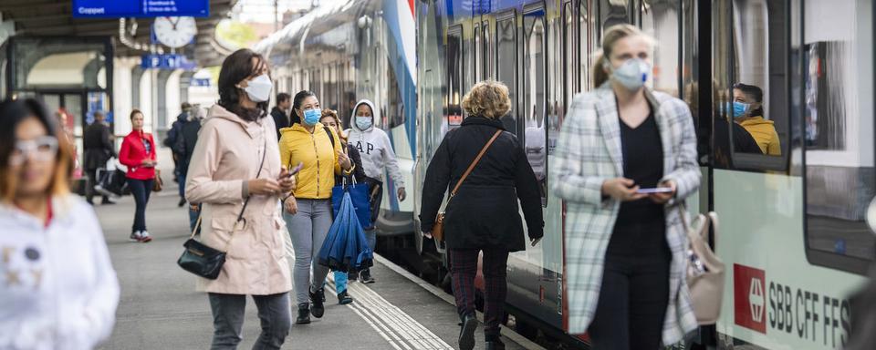 Des personnes prennent les transports publics un train des CFF certains avec des masques de protection et d'autres sans, ce mercredi 29 avril 2020 a Geneve. Le processus en vue d'un retour progressif a la normale de l'offre de transport. Un certain nombre d'elements doivent encore etre precises d'ici la. Il s'agit en particulier de tenir compte du concept de protection au niveau sanitaire du au Coronavirus Covis-19 pour les transports publics dans l'ensemble du pays, qui doit etre elabore d'ici au 29 avril par les CFF et CarPostal a la demande de la Confederation. [Keystone - Martial Trezzini]