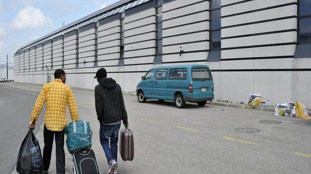 Deux demandeurs d’asile repartent devant le centre de requérants de La Chaux-de-Fonds en mai 2011. [Sandro Campardo / Keystone]