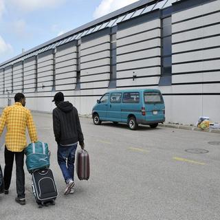Deux demandeurs d’asile repartent devant le centre de requérants de La Chaux-de-Fonds en mai 2011. [Sandro Campardo / Keystone]