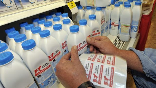 L'aide du canton du Valais intervient alors que les paysans suisses luttent pour un prix du lait plus équitable, comme ici en collant des étiquettes sur les litres de lait. [KEYSTONE - Martial Trezzini]