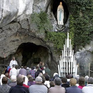 Des pèlerins priant devant la grotte de Lourdes. [Reuters]