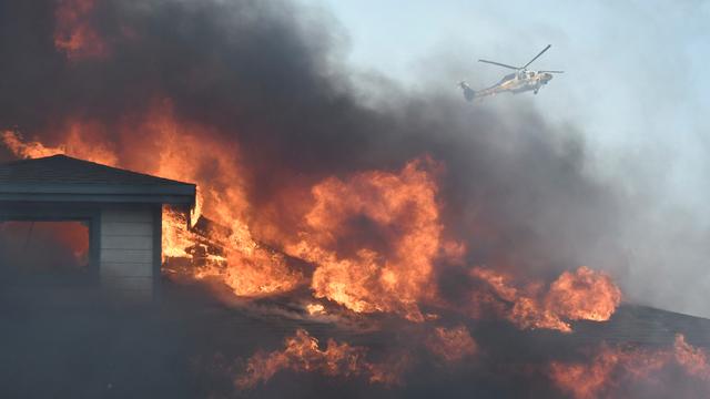 Un hélicoptère de lutte contre le feu survolant un quartier résidentiel de Los Angeles [Gene Blevins/reuters]