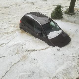 Une voiture sous l'eaux et les les grêlons, à Sonceboz, dans le Jura bernois. [Un habitant de Sonceboz (BE)]