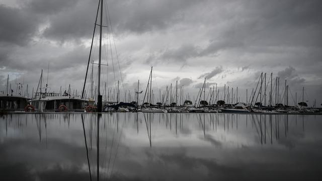 Les bateaux ancrés au port se reflètent dans une flaque d'eau après de fortes pluies avant la tempête Ciaran le 1er novembre 2023, à Arcachon, dans le sud-ouest de la France. [AFP - Philippe Lopez]