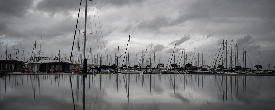 Les bateaux ancrés au port se reflètent dans une flaque d'eau après de fortes pluies avant la tempête Ciaran le 1er novembre 2023, à Arcachon, dans le sud-ouest de la France. [AFP - Philippe Lopez]