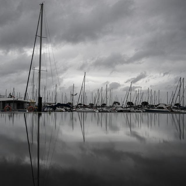 Les bateaux ancrés au port se reflètent dans une flaque d'eau après de fortes pluies avant la tempête Ciaran le 1er novembre 2023, à Arcachon, dans le sud-ouest de la France. [AFP - Philippe Lopez]